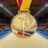 Медаль с изображением женщины в действии на фоне гимнастической арены, отмечающая достижения в гимнастике.