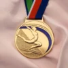 Золотая медаль с изображением женщины-гимнастки, символизирующая достижения в соревнованиях по гимнастике.