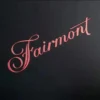 Texto "Fairmont" en rojo sobre fondo negro, en forma de adhesivo metálico, destacando un diseño atrevido y moderno.