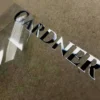 Una pegatina metálica que muestra la palabra "jardinero" sobre un papel, destacando un diseño limpio y moderno.