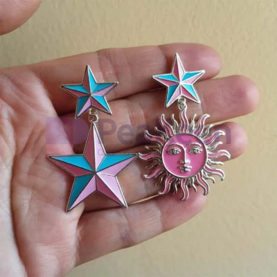 Custom enamel earrings featuring two stars and a sun design, adorned with vibrant blue enamel accents.