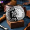A leather belt featuring a silver engraved buckle adorned with a crest, showcasing elegance and craftsmanship.