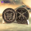 Primo piano di una moneta SWAT challenge che mostra il motivo ripetuto "swat" in un design di grande effetto.