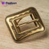 A brass belt buckle featuring a gold finish and a small square design, showcasing elegance and craftsmanship.