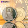 A Buddha coin displayed alongside a lit candle and an elegant candle holder, creating a serene atmosphere.