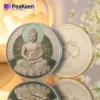 The Buddha coin is placed on a table surrounded by colorful flowers, representing harmony and serenity.