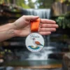 A person proudly holds a fiesta medal in front of a cascading waterfall, showcasing their achievement in a vibrant setting.