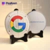 Logo di Google visualizzato su una piastra metallica con supporto, che ricorda il design di una moneta commemorativa.