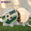 A soccer ball and a soccer-themed coin resting on a vibrant green soccer field.
