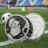 Two soccer referee coins featuring soccer balls, placed on a grassy field, ready for a match decision.