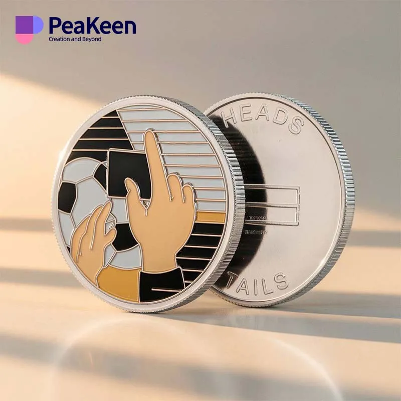 A coin featuring a hand holding a ball alongside a soccer ball, symbolizing soccer referee decisions.