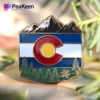 Pin de la bandera de Colorado con montañas y árboles, símbolo de la belleza natural y el orgullo del estado.