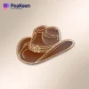 Alfiler de sombrero vaquero marrón sobre un fondo blanco limpio, que muestra su detallado diseño y artesanía.