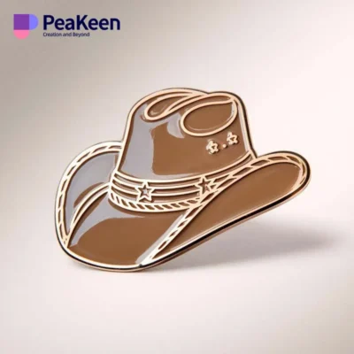 Brown cowboy hat pin displayed on a clean white background, showcasing its detailed design and craftsmanship.