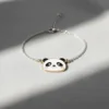 Enamel panda face charm on a silver chain bracelet, showcasing a cute and playful design.