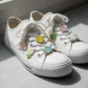 A pair of white sneakers adorned with colorful enamel charm pins, showcasing a playful and unique style.