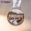 A gold finisher medal featuring the word "Finisher" prominently displayed on its surface.