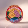 Vibrant enamel pin displaying "love love love," representing LGBT pride and the celebration of love in all forms.