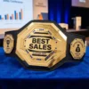 Gold best sales champion belt trophy with custom text, featuring Top Performer and Record Breaker side plates, displayed at a corporate conference