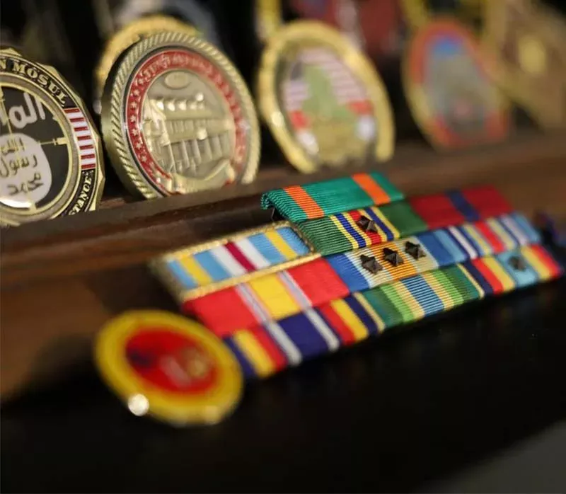 A display of challenge coins and ribbons arranged neatly on a table, showcasing achievements and honors.