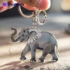 A person holding a metal keychain featuring a detailed elephant design.