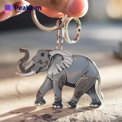 A person holding a metal keychain featuring a detailed elephant design.