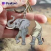 A hand displaying a metal keychain shaped like an elephant, emphasizing its unique design.