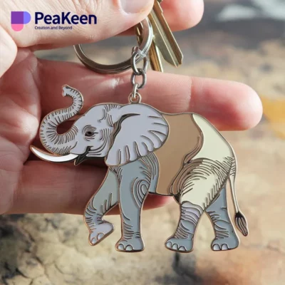 A hand displaying a metal keychain shaped like an elephant, emphasizing its unique design.