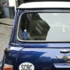 A blue mini vehicle displaying a sticker adorned with masonic emblems on the rear window.