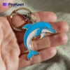 A hand holding a metal dolphin keychain, showcasing its sleek design and vibrant details.