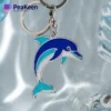 Close-up of a metal dolphin keychain on a blue background, emphasizing its detailed design and playful aesthetic.