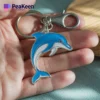 A person holds a metal dolphin keychain in their hand, showcasing its intricate design and shiny finish.