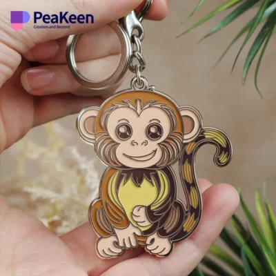 A soft enamel monkey keychain is cradled in a hand, emphasizing its playful appearance and intricate details.