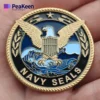 A Navy SEAL badge rests in a hand, representing valor, accompanied by a Navy SEAL challenge coin.