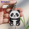 A soft enamel panda bear keychain is held in a person's hand, showcasing its cute design and vibrant colors.