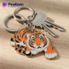A soft enamel tiger keychain holding two keys, showcasing vibrant colors and intricate design details.