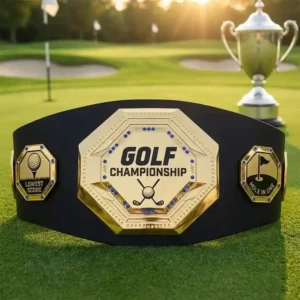 Gold golf championship belt trophy featuring Lowest Score and Hole in One side plates on a golf course background