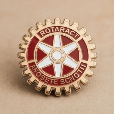 A stylish Rotaract pin in red and gold, prominently featuring the word "rotatrici" for recognition and pride.