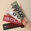 A hand displays four leather tags in different colors, connected by a woven keychain, highlighting their unique designs.