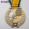 Una medaglia di badminton con il disegno di una racchetta e un nastro colorato, che simboleggia i risultati ottenuti in questo sport.