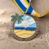 Una medalla de voley playa con palmeras y un balón de playa, símbolo de los logros en este deporte.