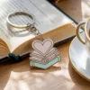 كتاب، وكوب شاي، وسلسلة مفاتيح تتميز بحلية على شكل قلب، مثالية لمحبي الكتب.