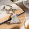 كتاب مع سلسلة مفاتيح تتميز بتصميم عاشق للكتب ترتكز فوقه سلسلة مفاتيح.