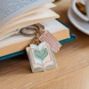 كائن على شكل قلب وسلسلة مفاتيح ترتكز على كتاب، مما يمثل شغف عشاق الكتب.