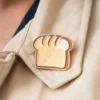 A person wearing a whimsical pin shaped like a slice of bread on their clothing.