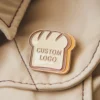 A decorative pin depicting a piece of bread, ideal for bread lovers and accessory collectors.