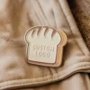 A whimsical pin with a bread logo, ideal for bread lovers and collectors of unique accessories.