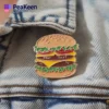 Eine Person trägt stolz eine Hamburger-Anstecknadel an ihrer Kleidung und zeigt damit ihre Liebe zum Essen und zu einzigartigen Accessoires.