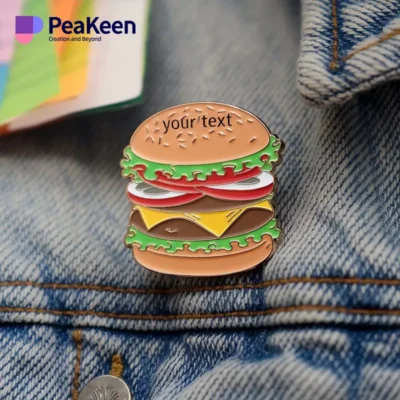 Épingle en émail représentant un hamburger, conçue pour les passionnés qui souhaitent enrichir leur collection ou leur tenue.