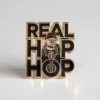 A pin featuring the phrase "Real Hip Hop" in bold letters, representing hip hop culture and style.
